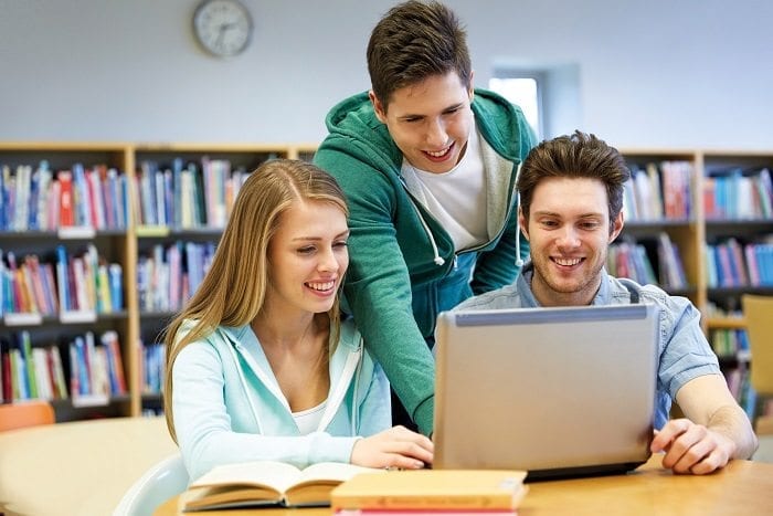 happy students with laptop in library